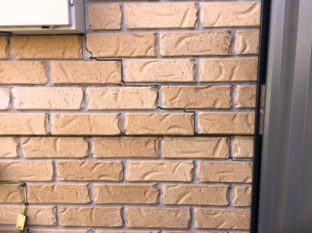 Brick wall with extensive cracks indicating subsidence and potential foundation repair needs.